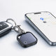 Traceur Bluetooth porte-clé accroché à des clés de voiture, position affichée sur la carte d'un smartphone
